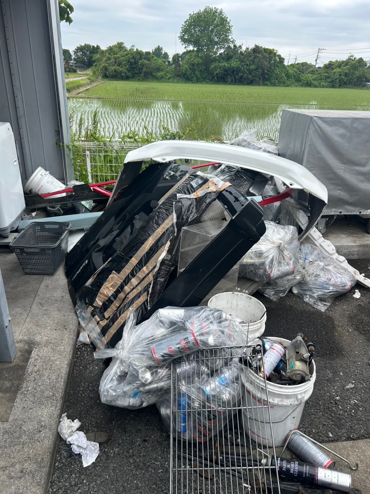 事業所敷地脇に山積みになった自動車部品と廃材